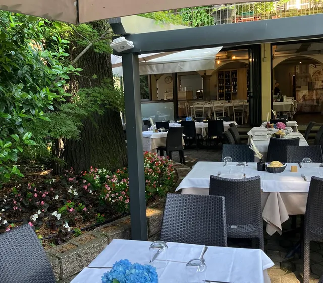 Tavoli apparecchiati in giardino, tra gli alberi e i fiori