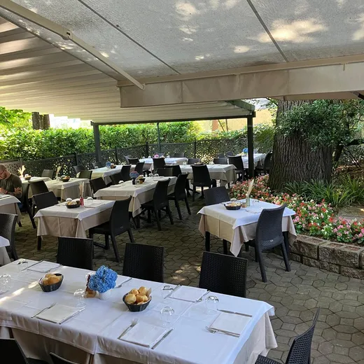 Tavoli sotto il porticato, accanto al grande albero del giardino